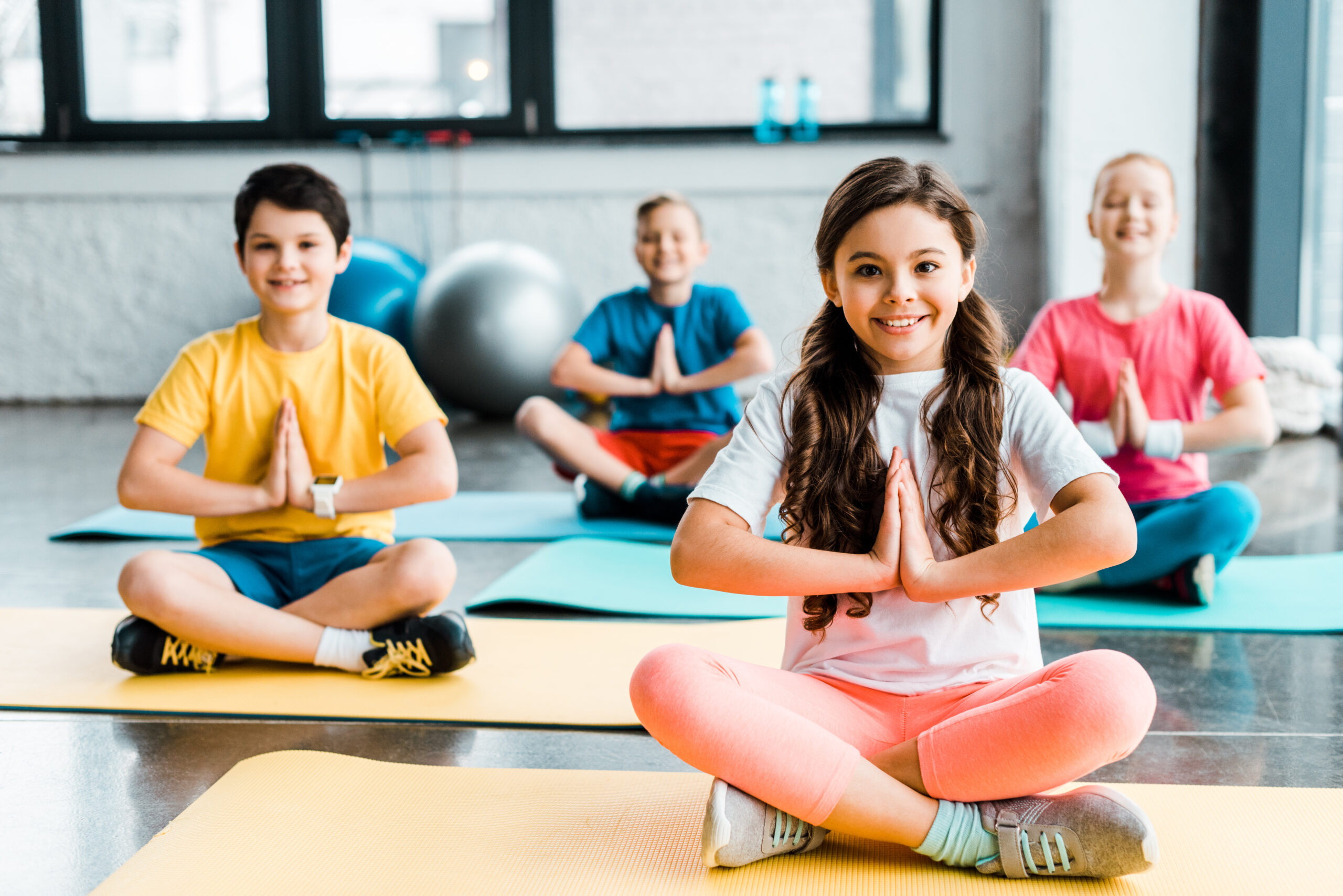 Cheerful kids smiling while stretching on fitness mats